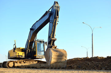 Excavator digs the ground for the foundation and construction of a new building. Road repair, asphalt replacement, renovating a section of a highway, laying or replacement of underground sewer pipes