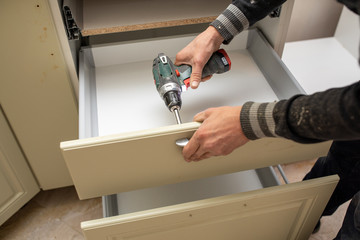 Man using electronic drill to install a cabinet