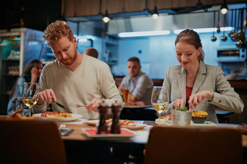 Handsome cucasian couple sitting in restaurant and eating dinner.
