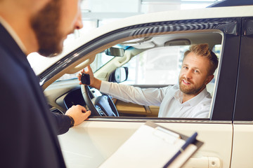 Car dealer showing automobile to client.