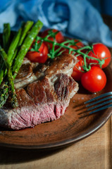 veal steak in the section of medium roast. on a wooden board with tomatoes and asparagus