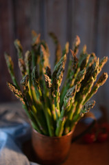 green asparagus in old cup on table with towel