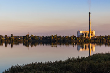 Old waste processing plant at the lake. Sunset