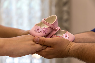 Loving couple holding pink baby girl shoes with care and support