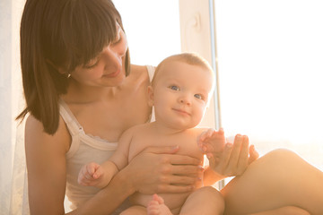Mother with baby in room at home near window