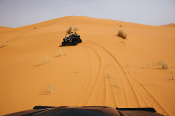 Fototapeta na wymiar Off road buggies crossing dunes in the desert. Rally raid adventure.