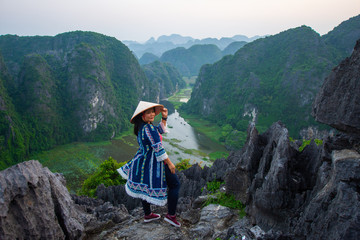 Fototapeta na wymiar happy woman stand on peak of mountain at Mua Cave, Ninh Binh, Vietnam at evening, subject is blurred, low key and noise.