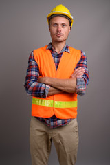 Portrait of handsome man construction worker against gray background