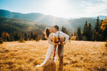 Newlyweds kissing at sunset in the mountains. © Yuliia