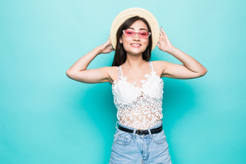 Naklejka premium Young asian woman with sunglasses and straw hat standing isolated on green background