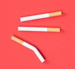Three cigarettes isolated on red background
