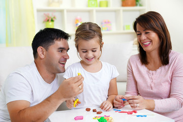     Family playing with Plasticine, making  colorful shapes   