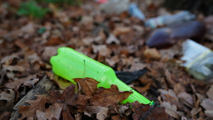 Garbage in the Park or forest, an empty bottle lying on the ground. The concept of environmental pollution, environmental problems of nature.