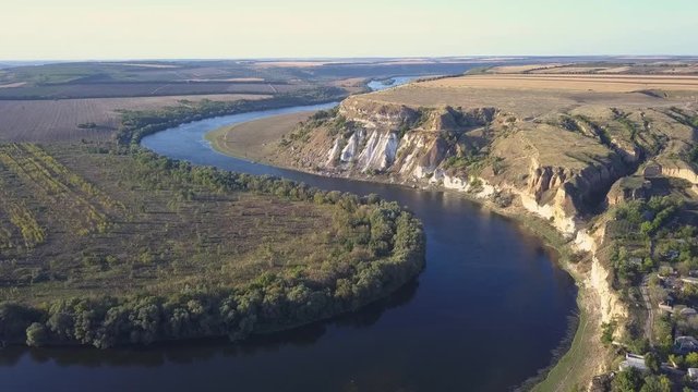 Top view of Dnestr (Dniester) river in autumn. River surrounds yellow field and green forest. Moldova republic of.