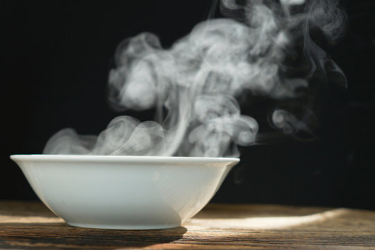 bowl of hot soup with steaming on wooden table on black background. Hot food consept.