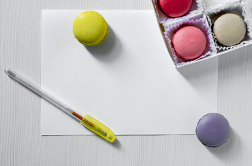 Macaroons cookies on a table next to a postcard and pen. view from above.