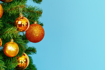 Christmas tree with golden baubles close up on blue background