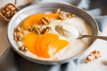Yogurt with peach, nuts and honey in a bowl