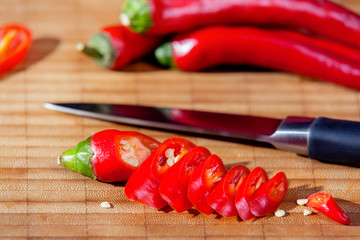 Spicy red chili pepper sliced with the knife on the cutting board
