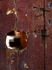 An old wooden door has a hole through which you can peek into the courtyard
