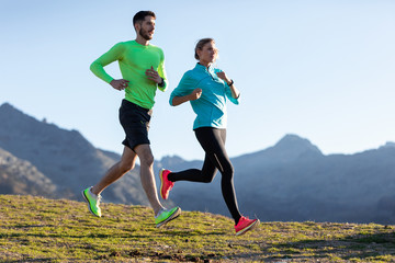 Healthy young couple running on mountain trail in the morning.