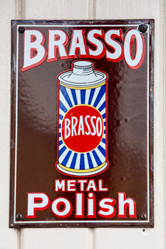 NR SOUTHAMPTON,UK - 25 June 2013: Old style tin advertising board for Brasso Metal Polish displayed on painted wood background. On 25 June 2013 Near Southampton UK