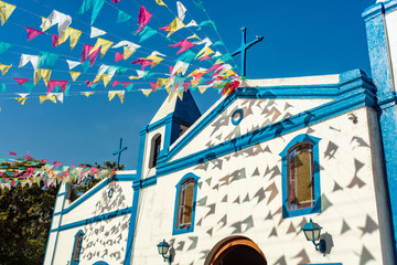 Church Chapel Sao Joao Batista, in Ilhabela, north coast of Sao Paulo, Brazil, decorated with typical party celebration Junina flags. - obrazy, fototapety, plakaty