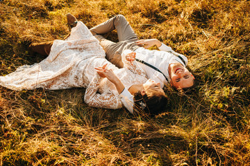 Happy young couple lying on the grass in autumn time. Romantic setting