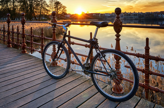 Bicycle on a bridge with sunset in the background.