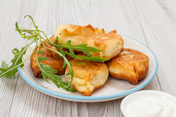 Plate with fried pies on wooden boards.