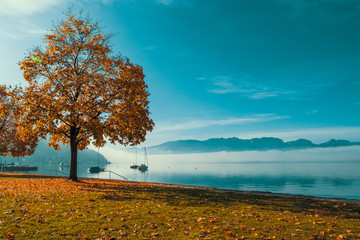 Backlit view of boats anchored at the Traunsee in Gmunden, OÖ, Austria with the Grünberg and the...