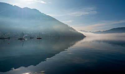 Backlit view of boats anchored at the Traunsee in Gmunden, OÖ, Austria with the Grünberg rising in the background
