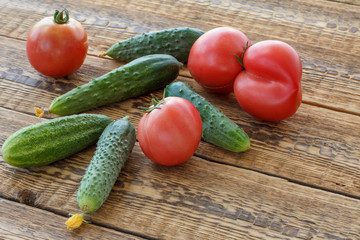 Cucumbers with tomatoes on old wooden boards.