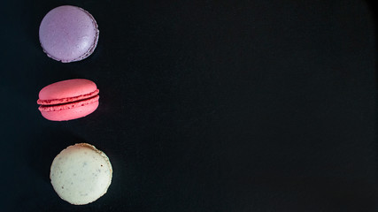 Obraz na płótnie Canvas Macaroons cookies on a dark canvas background. view from above.