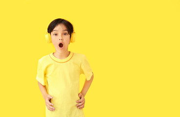 Surprised little boy listening to music on color background