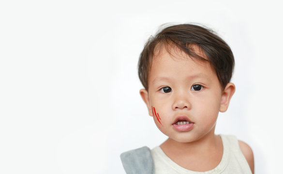 Portrait of little Asian baby boy with face make up sticker lesion on face in Halloween costume looking camera over white background.