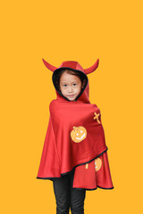 Peaceful little Asian child girl dressed Halloween costume. Kid in Dracula robe isolated on orange background.