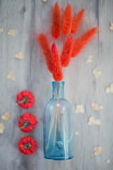 red dried grass in blue glass vase and small pumpkins