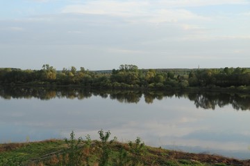Summer landscape or view of the river and banks with green grass and trees