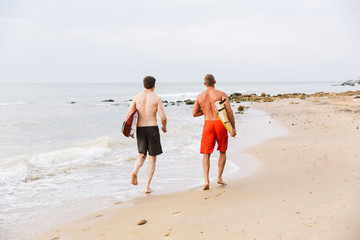 Fototapeta na wymiar Two men surfers friends on a beach outside.