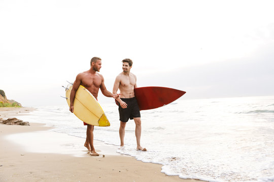 Two men surfers friends with surfings on a beach