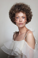 Vintage style portrait of young beautiful woman with curly hair and fancy makeup