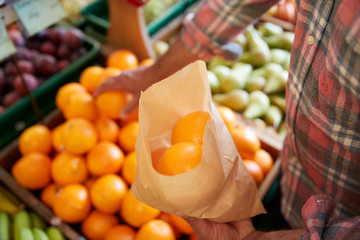 Close Up Of Male Customer With Paper Bag Buying Fresh Oranges In Organic Farm Shop