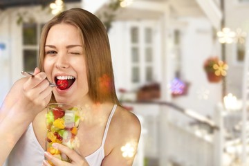 Young woman eating fruits from glass on blurred background