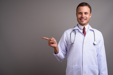 Portrait of handsome man doctor against gray background