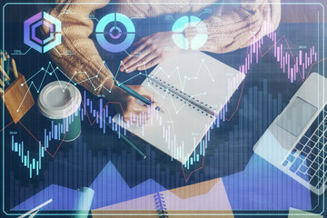 Forex graph on hand taking notes background. Concept of research. Double exposure