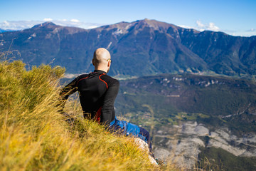 Fototapeta na wymiar Traveler man sitting on a hill of beautiful alpine landscape