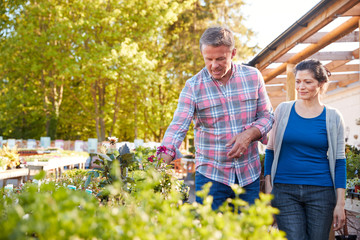 Mature Couple Outdoors Choosing Plants To Buy At Garden Center