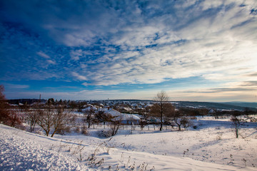 Sunrise and a snowy winter scene, and a setting moon over a small village