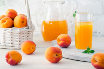 Glass and carafe with apricot juice and apricot fruits in basket